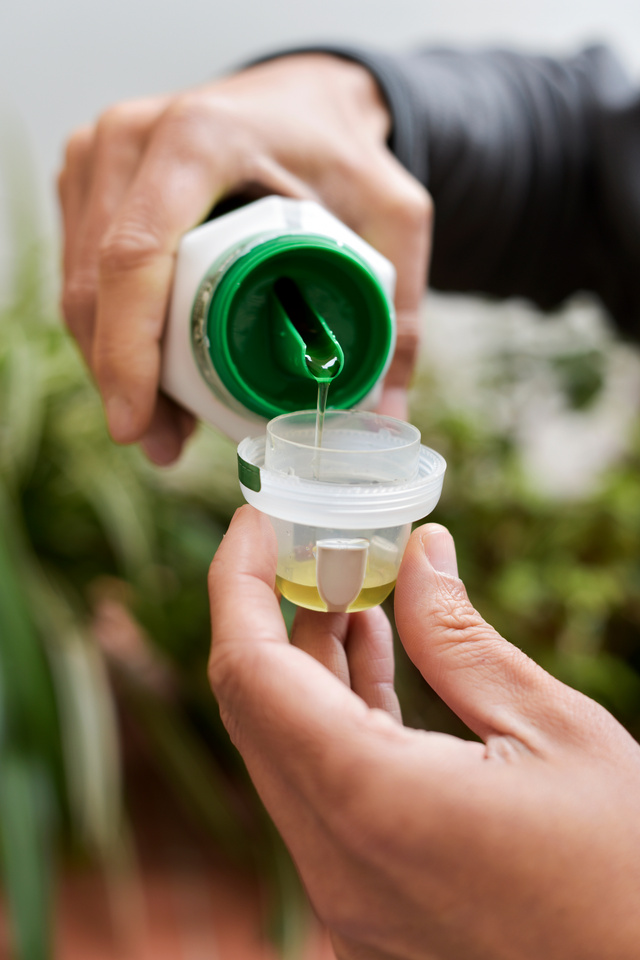 Man Measuring a Dose of Liquid Fertilizer